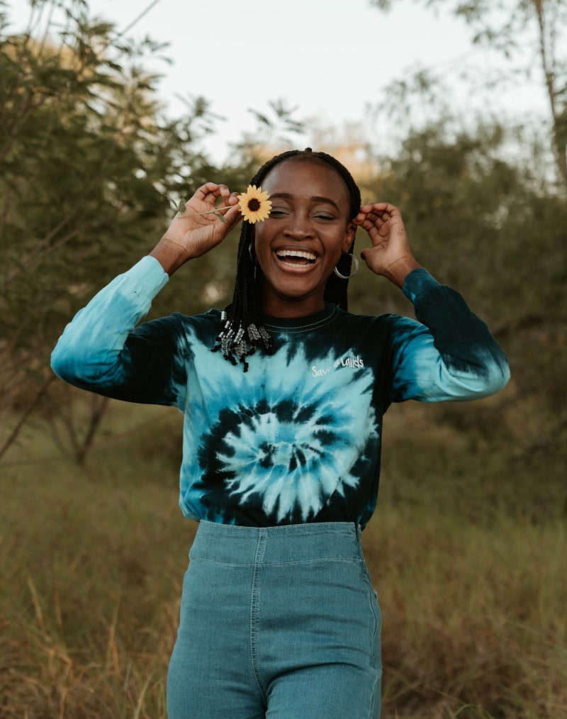 woman holding flower and smiling near a Denver dispensary