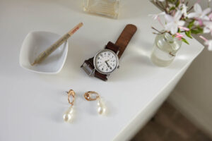 Stylish watch with leather band set at 4:20 with cannabis joint on sidetable with lamp, flowers, and earings.