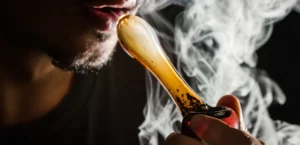 man smoking marijuana from a glass pipe